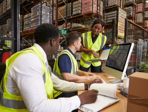 Two men in safety vests listening to a woman giving logistics directions